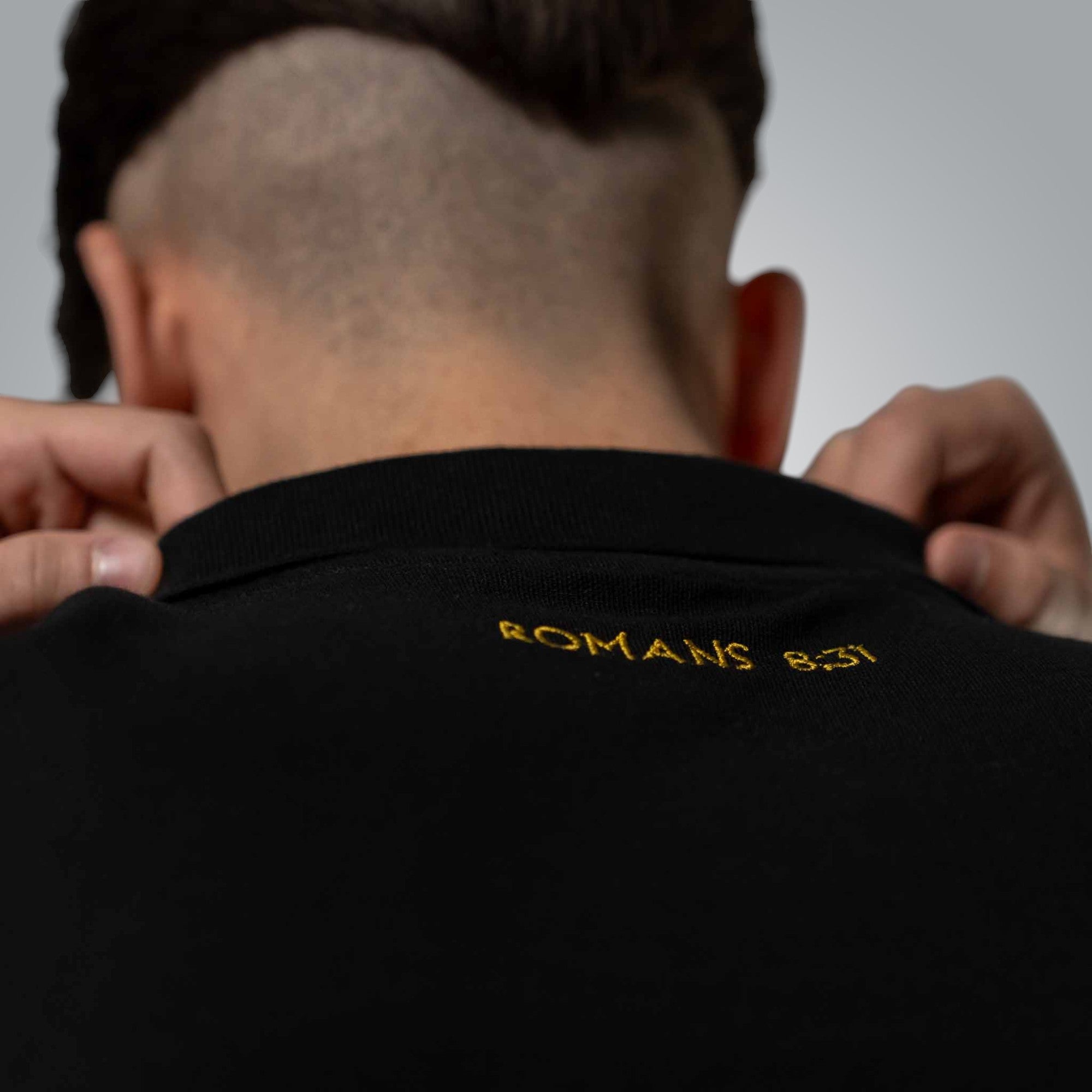 Back of black polo shirt with subtle Romans 8:31 embroidery meaning 'If God is for us, who can be against us