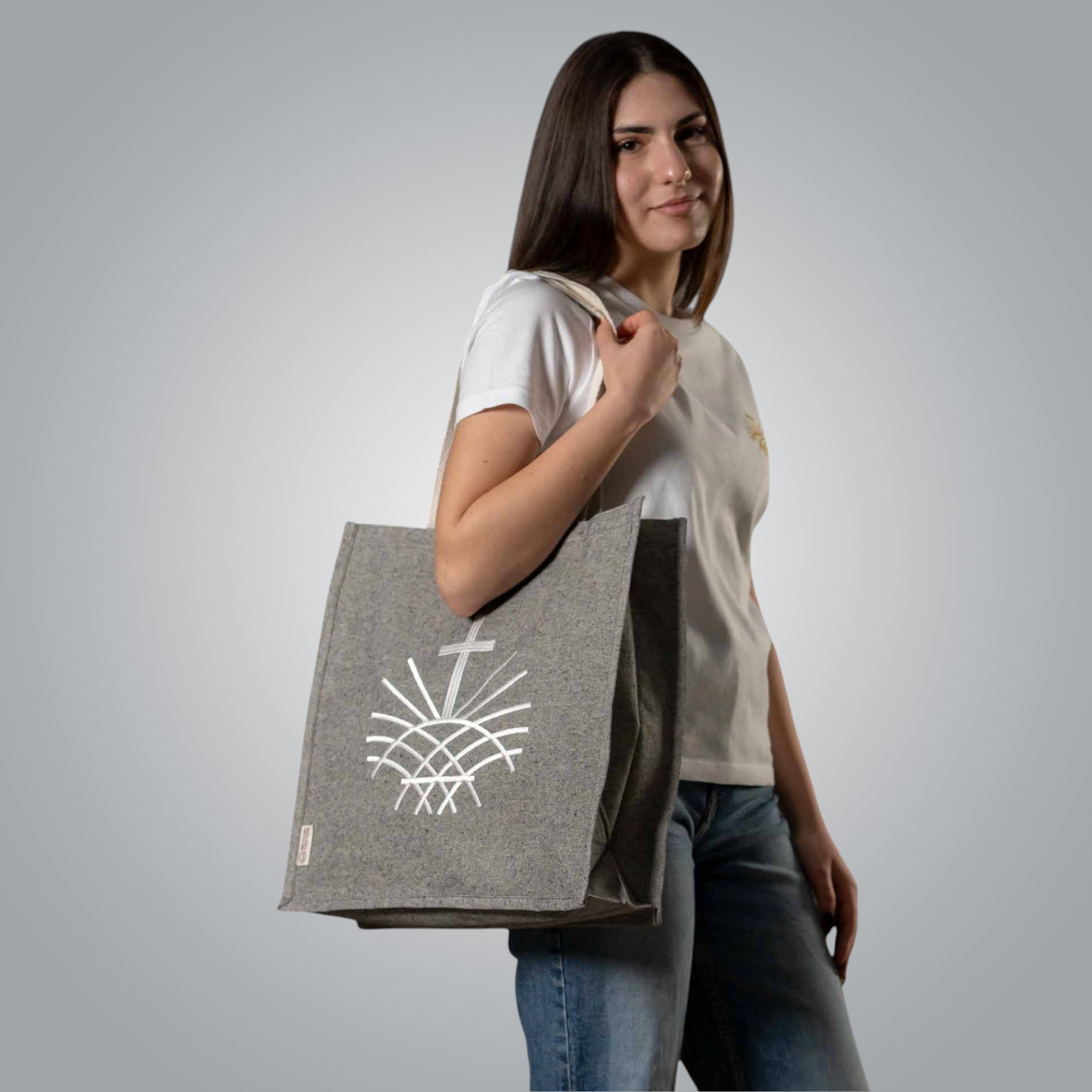 Woman carrying grey tote bag with white embroidered Loom in Light logo