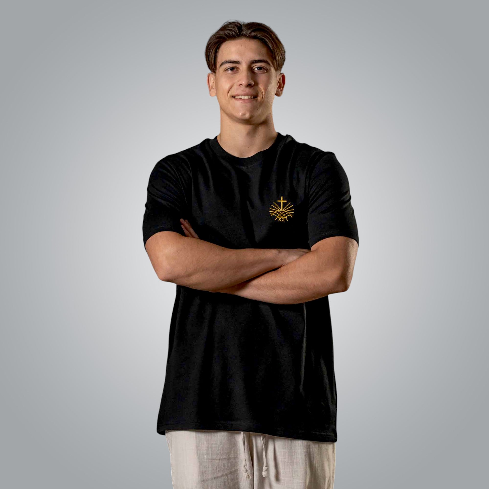 Front view of man in black Christian t shirt with gold embroidered chest emblem