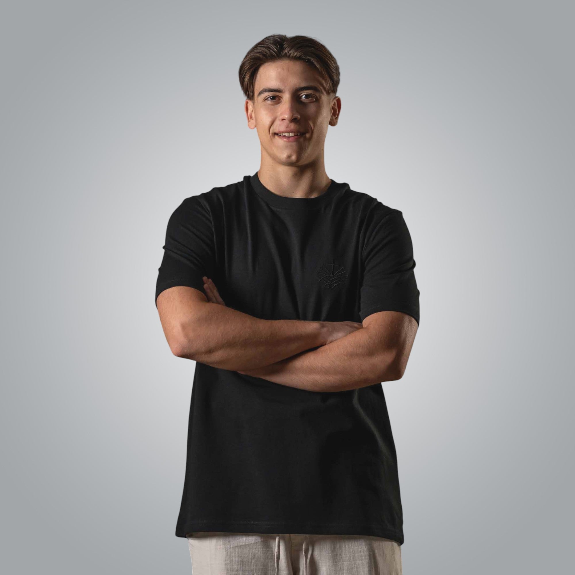 Man wearing black Christian t shirt with black embroidered Loom in Light logo on the chest