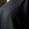 Close up of black embroidered Loom in Light emblem on black men’s t shirt