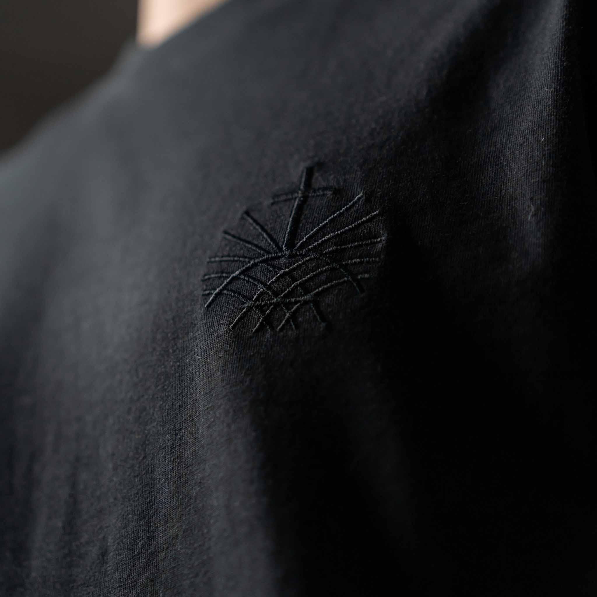 Close up of black embroidered Loom in Light emblem on black men’s t shirt