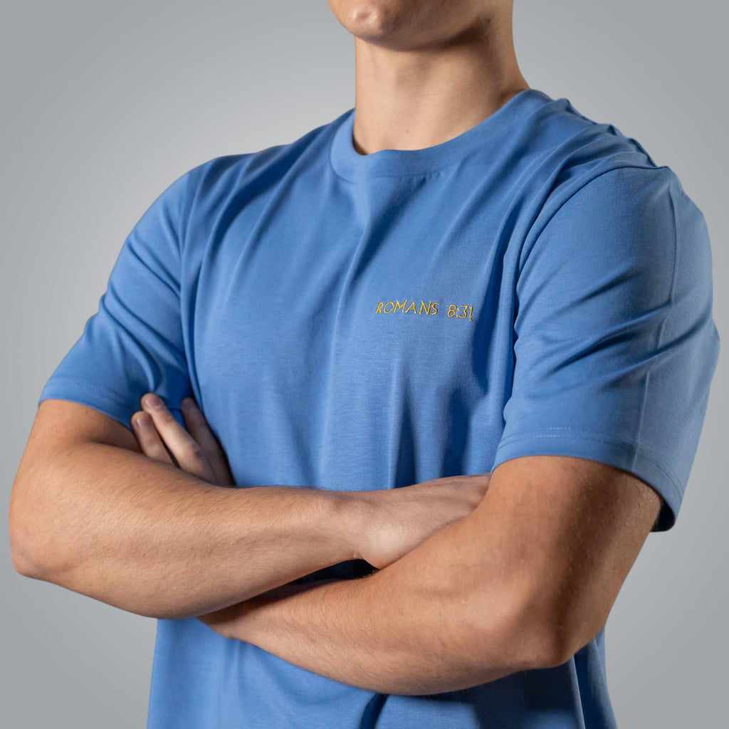 Close up of gold embroidered Romans 8:31 text on blue men’s Christian t shirt