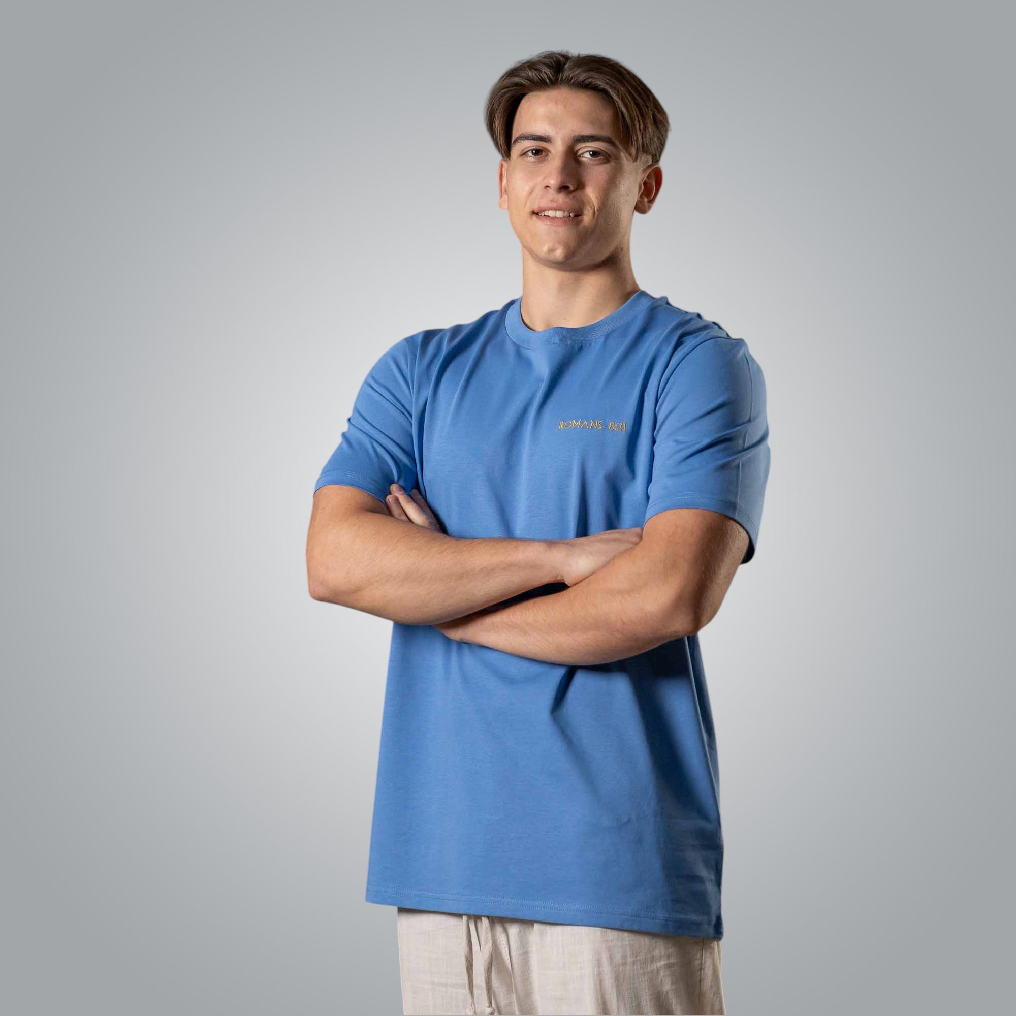 Front view of man in blue Christian t shirt with gold embroidered Bible verse on the chest