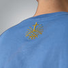 Close up of gold embroidered Loom in Light emblem on blue men’s t shirt