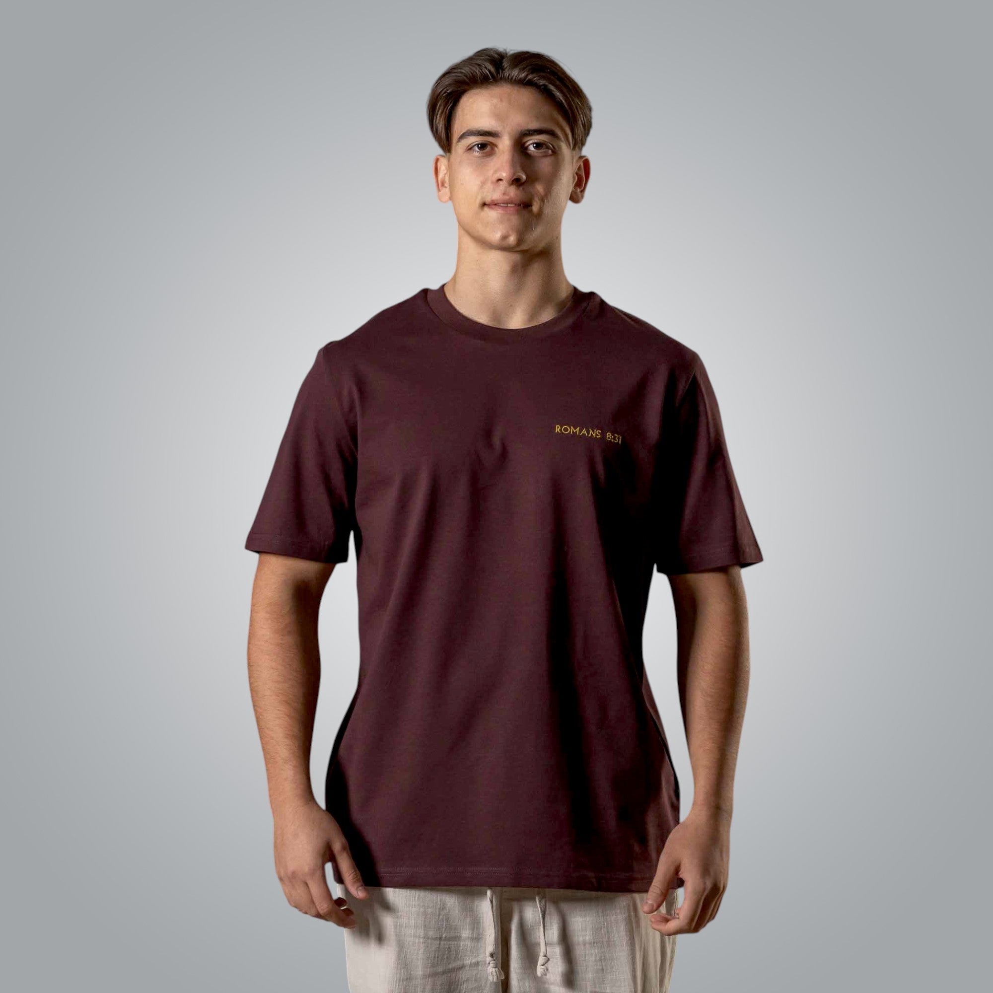 Man wearing burgundy Christian t shirt with gold embroidered Romans 8:31 text on the chest