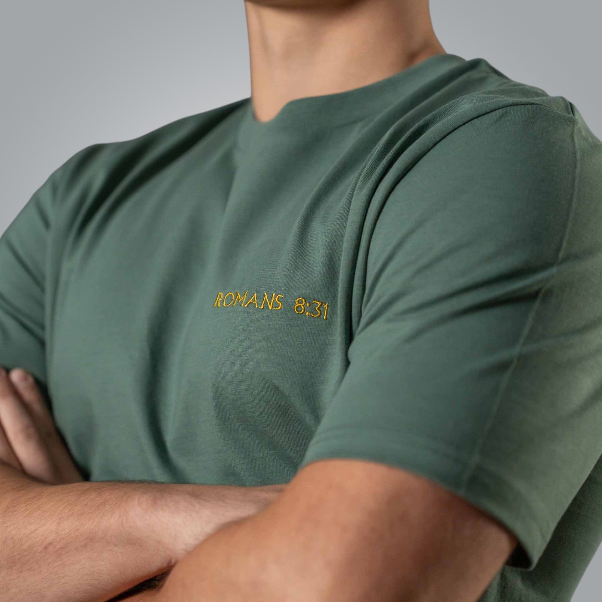Close up of gold embroidered Romans 8:31 on green men’s Christian t shirt