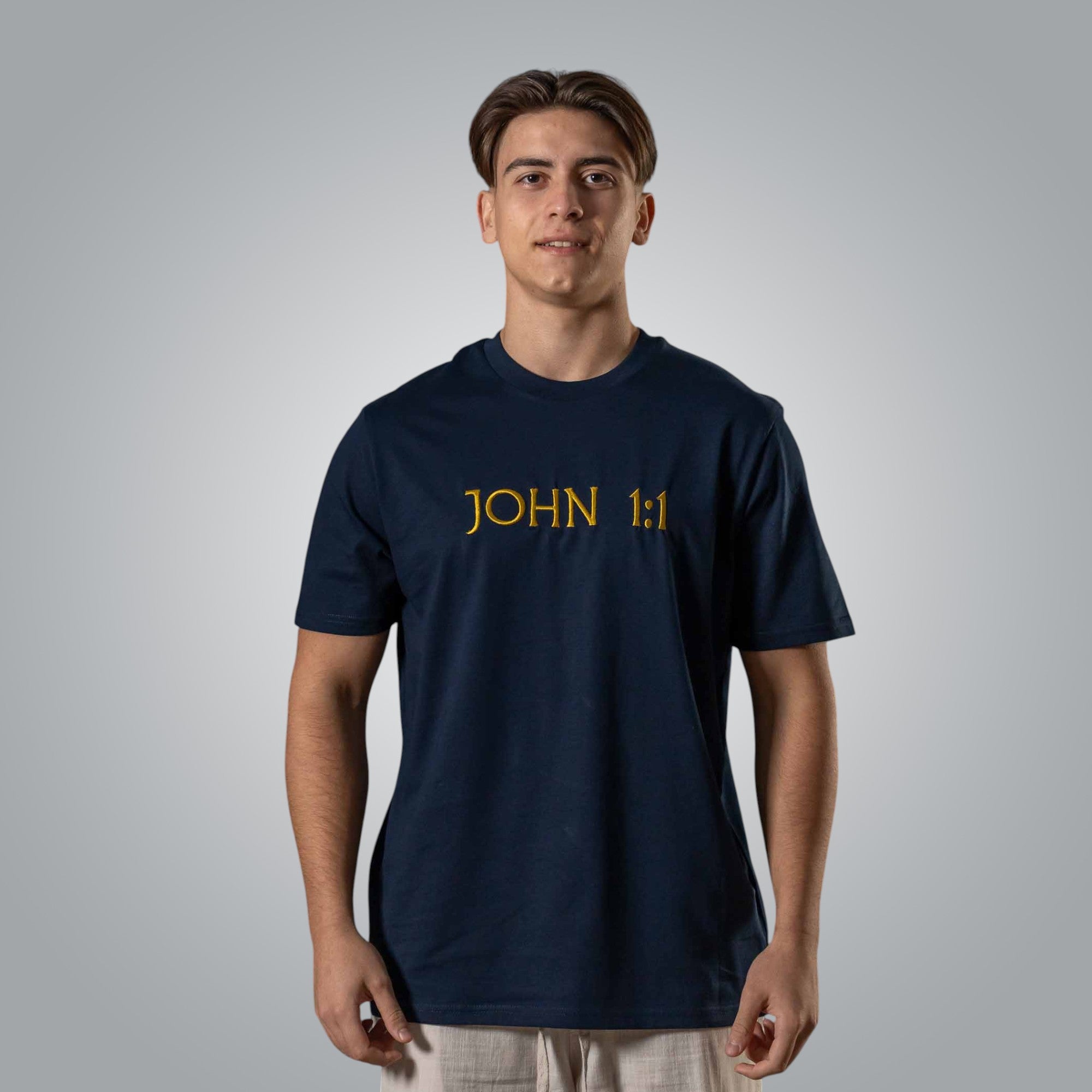 Man wearing navy Christian t shirt with gold embroidered John 1:1 text on the chest
