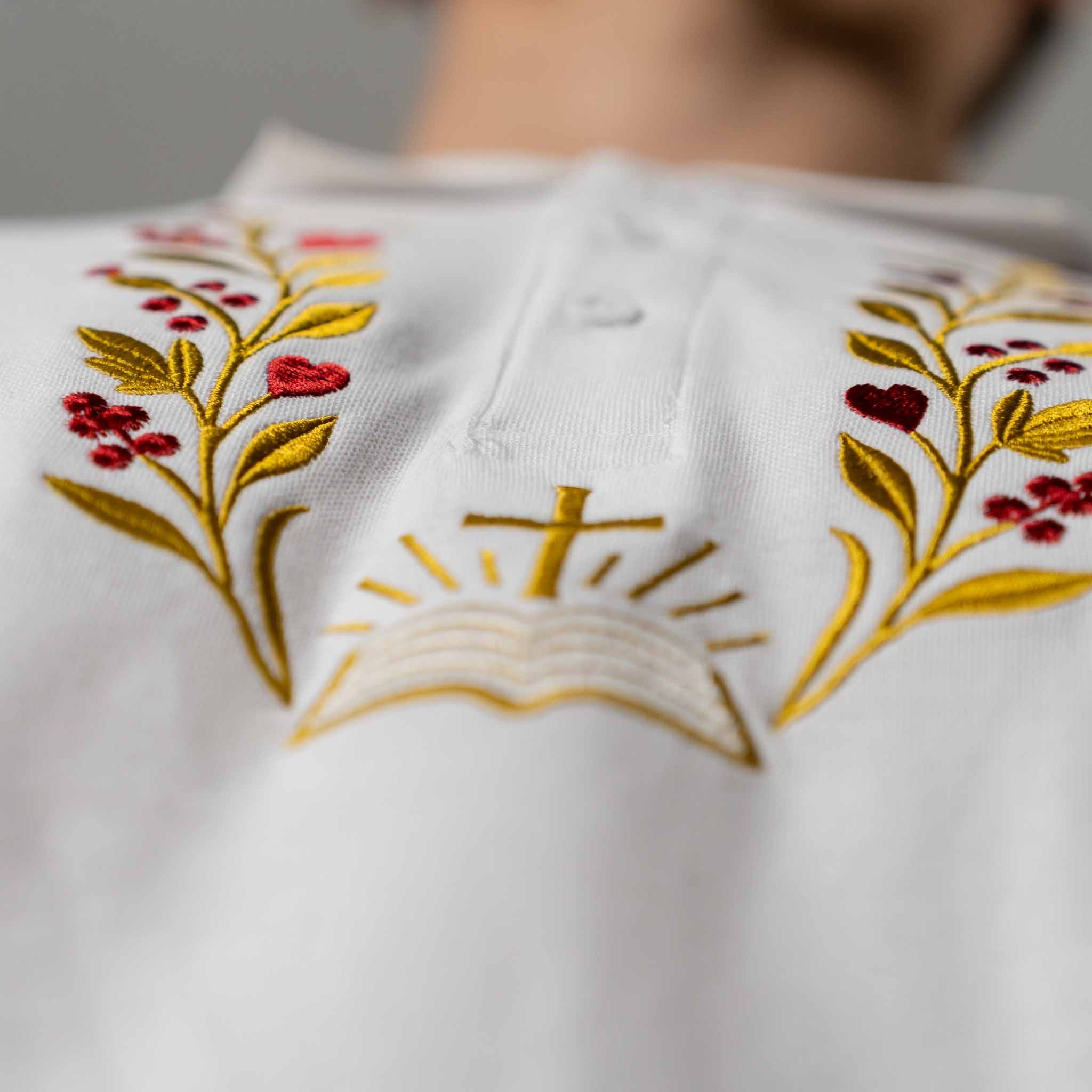 Macro detail of gold and red embroidery of branches and open Bible on men’s Christian polo