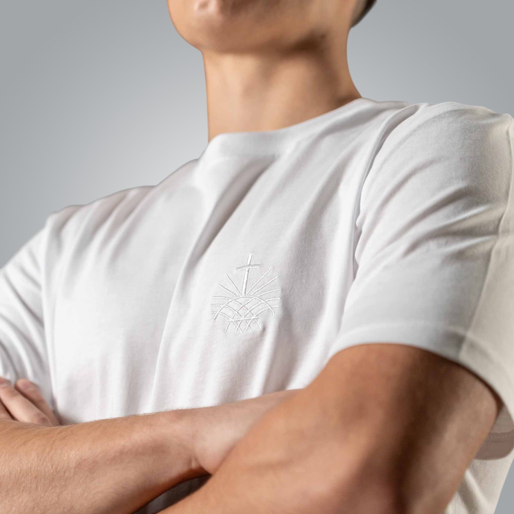 Close up of white embroidered Loom in Light emblem on men’s white Christian t shirt