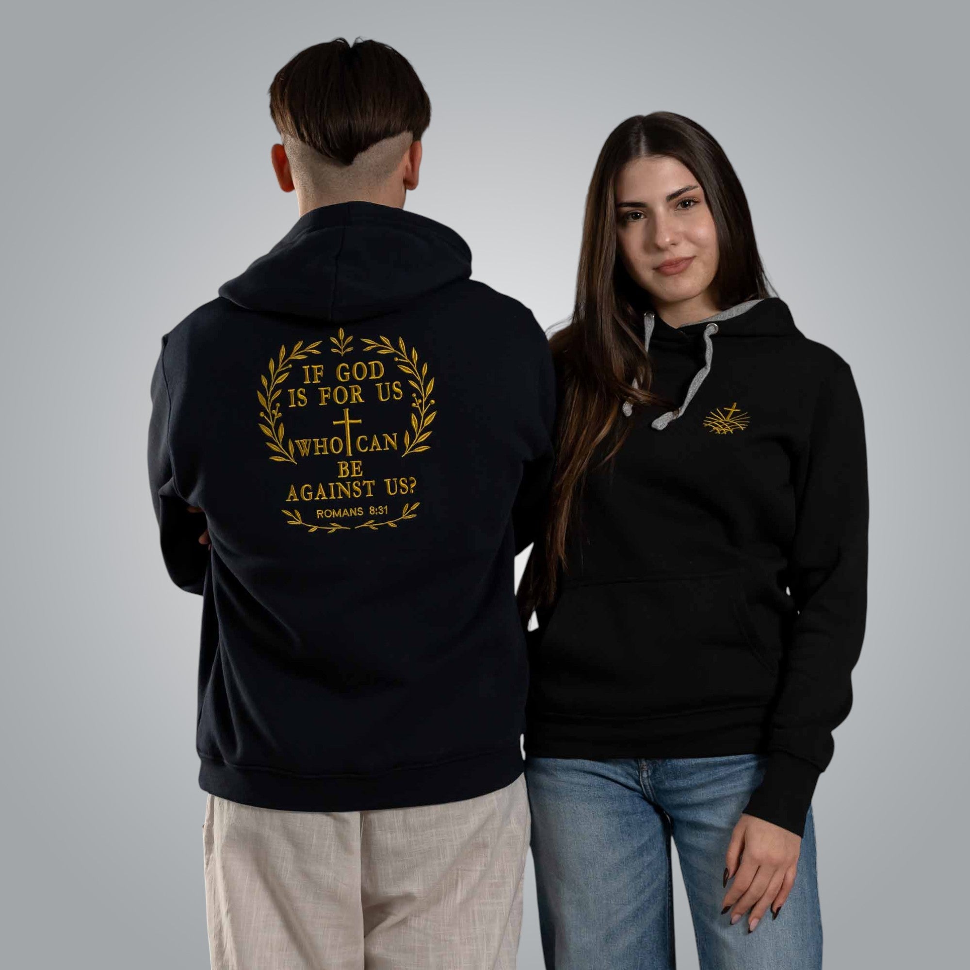 Man and woman wearing black hoodies with embroidered Loom in Light logo and Romans 8:31 design on the back