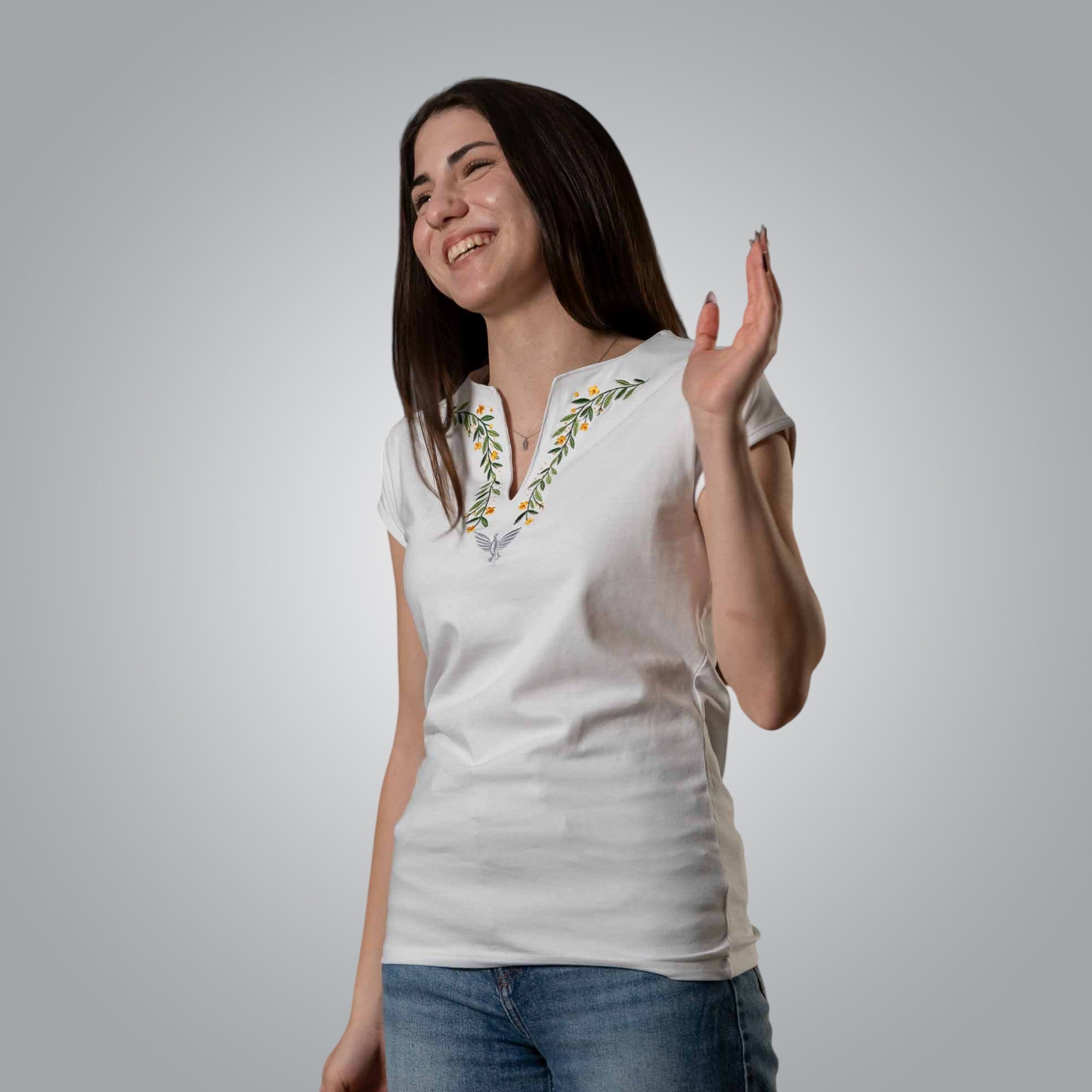 Woman wearing white Christian V neck t shirt with floral and dove embroidery in joyful pose