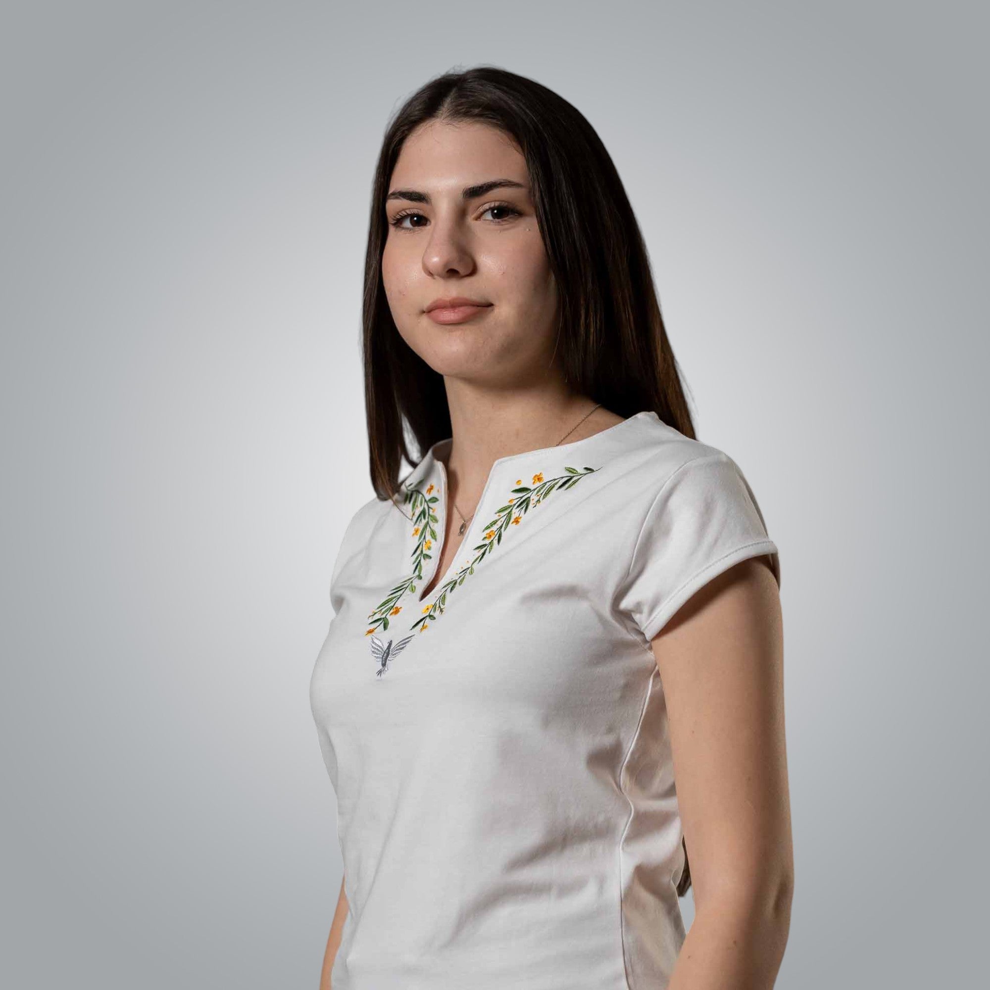 Woman in white V neck Christian t shirt showing embroidered dove motif inspired by the Lord’s Prayer